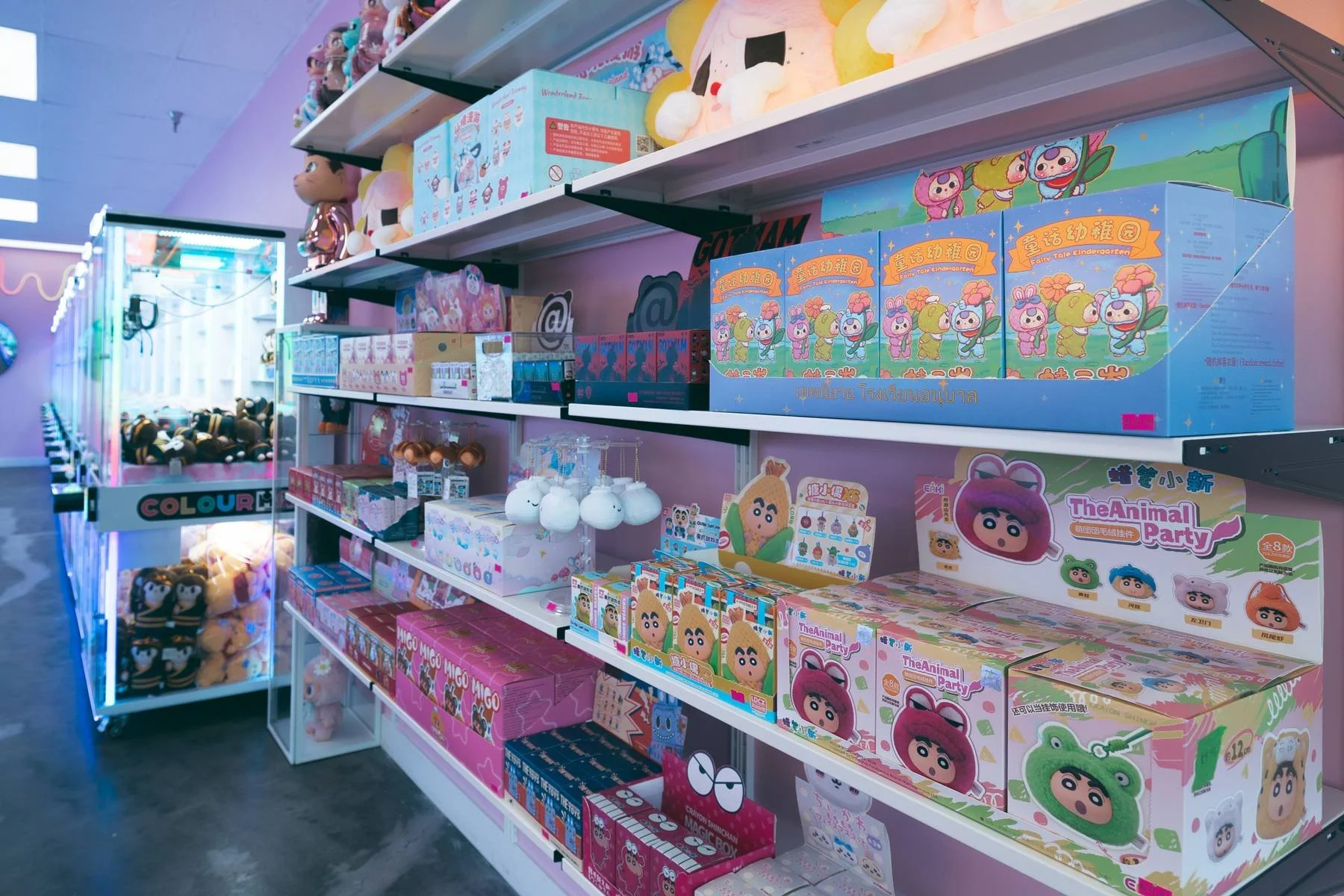 Retail store shelf displaying various toys and plush toys, with a colorful arcade claw machine in the background.