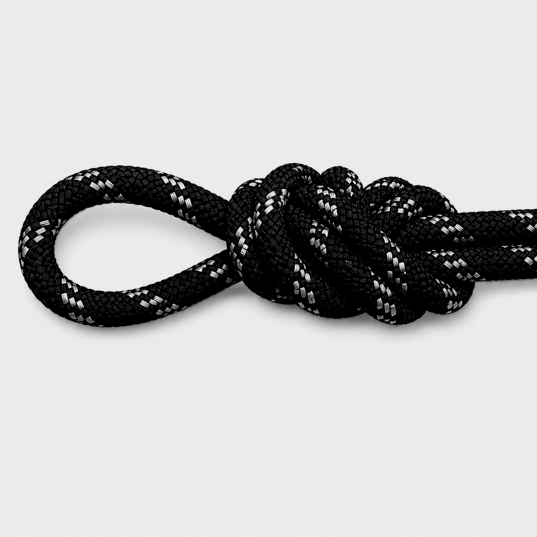 Close-up of a black shoelace with a white stripe pattern, tied in a knot on a white background.