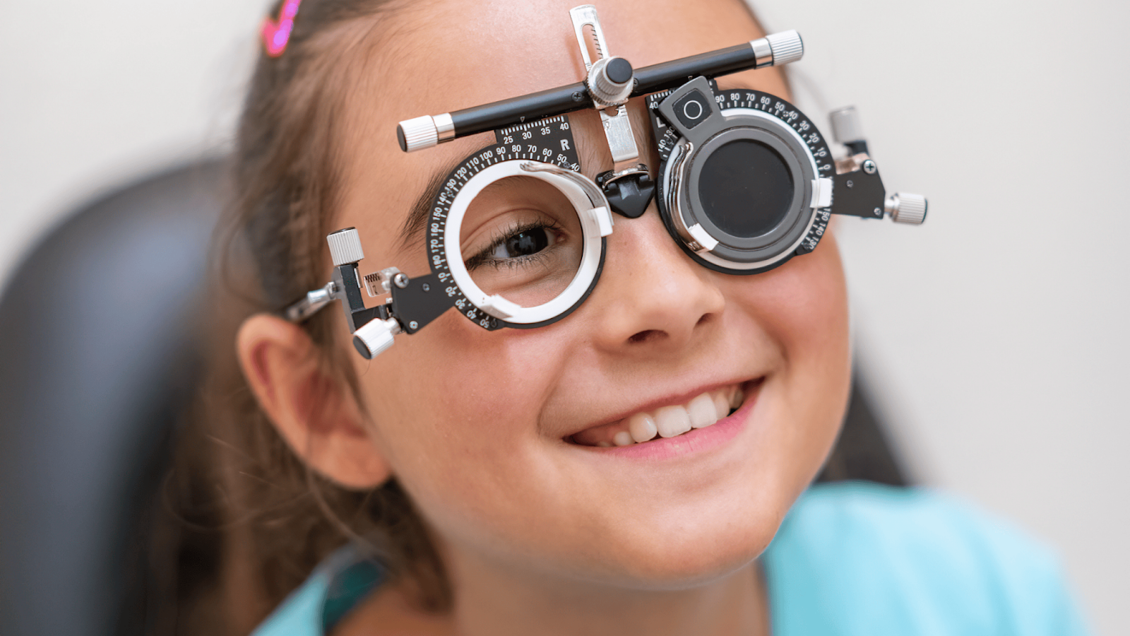 Young girl smiling while wearing eye examination trial frame.