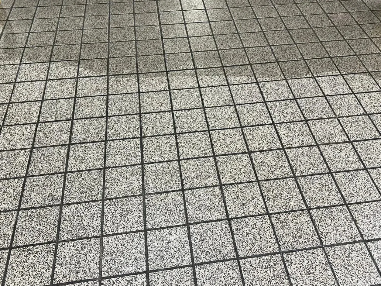 Close-up of a tiled floor with small square tiles and black grout lines.