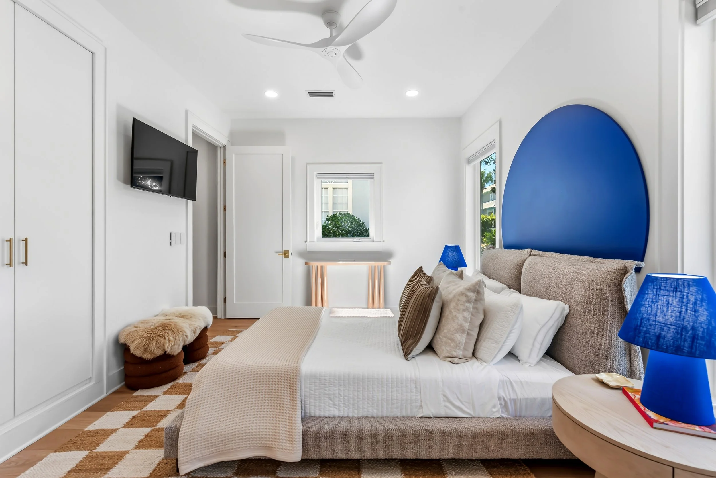 Sun-filled primary suite with a king bed, thoughtful interior design, and vibrant blue accents, complete with a smart TV and a private ensuite bathroom.