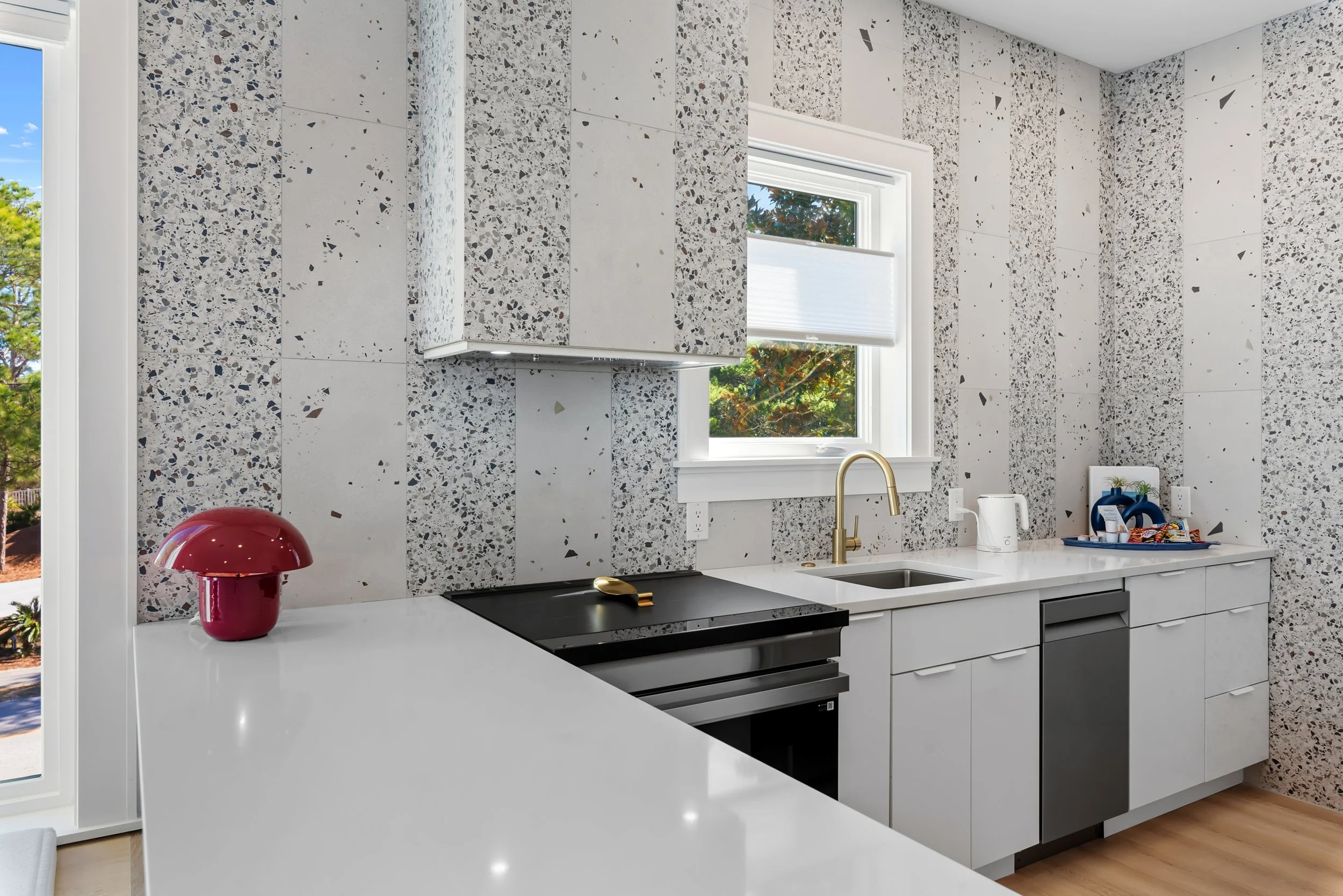 Bright, modern guest house kitchen with custom cabinetry, terrazzo backsplash, and stainless steel appliances near 30A.
