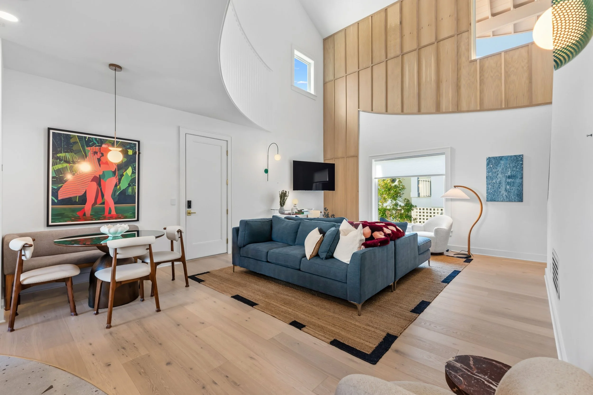 Light-filled, double-height living room with custom millwork, warm wood finishes, and an open, modern coastal layout.