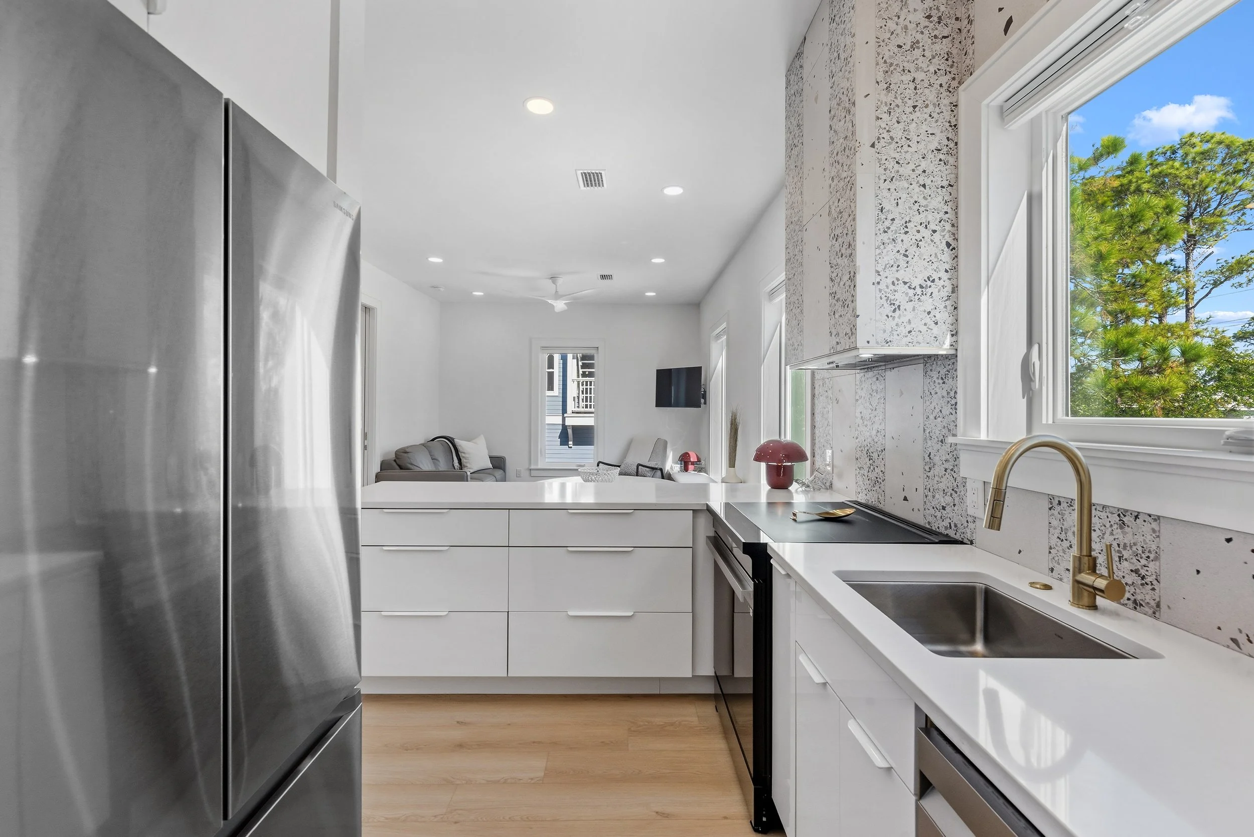 Bright, modern guest house kitchen with custom cabinetry, terrazzo backsplash, and stainless steel appliances near 30A.