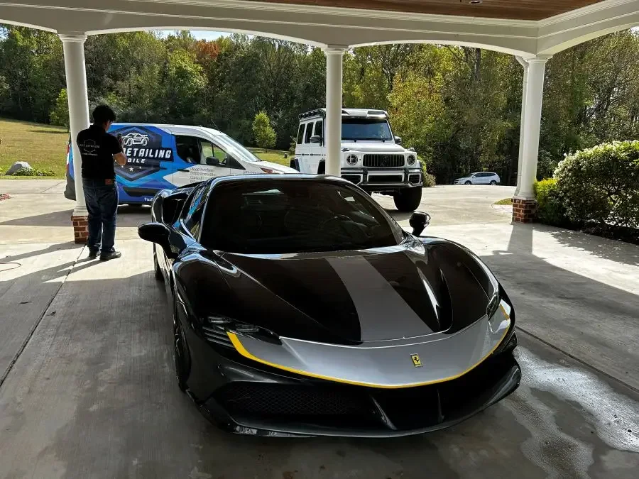 Fizz Mobile Detailing van on-site servicing a black Ferrari. High-end paint correction and detailing for exotic cars in The Ledges