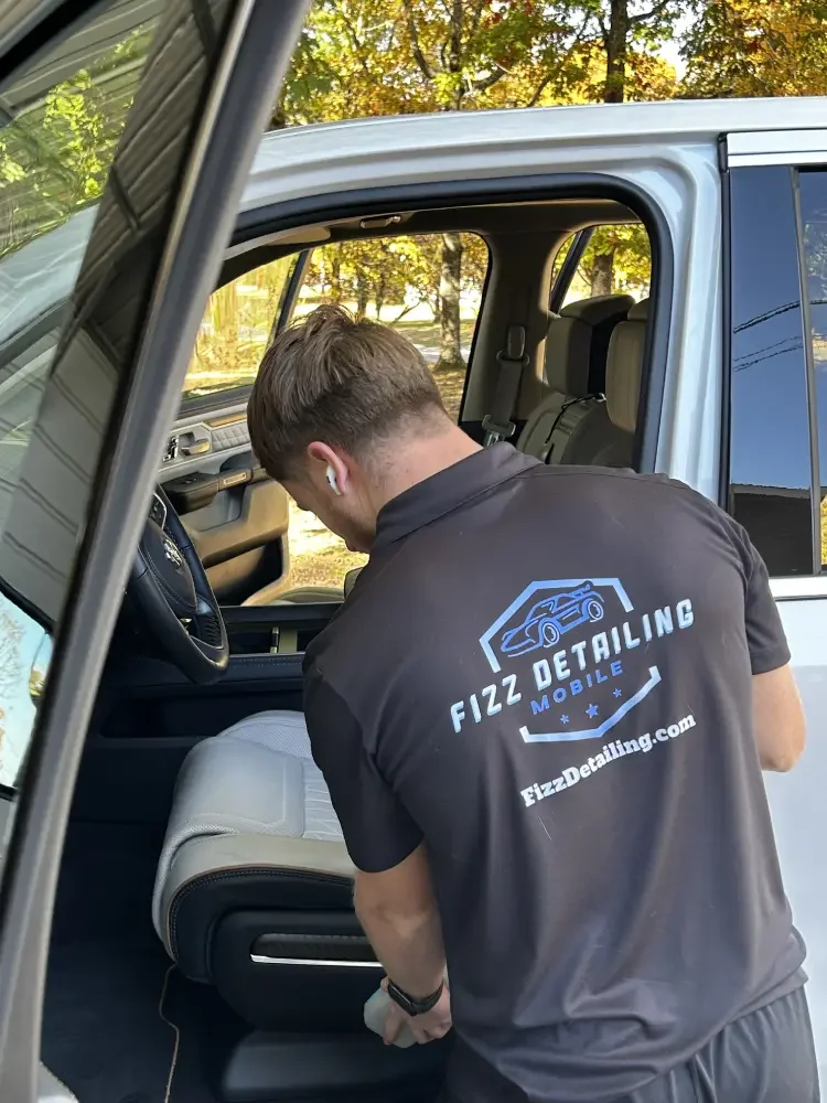 Interior mobile detailing service in progress. Technician steam cleaning upholstery and dashboard for a fresh, spotless finish.