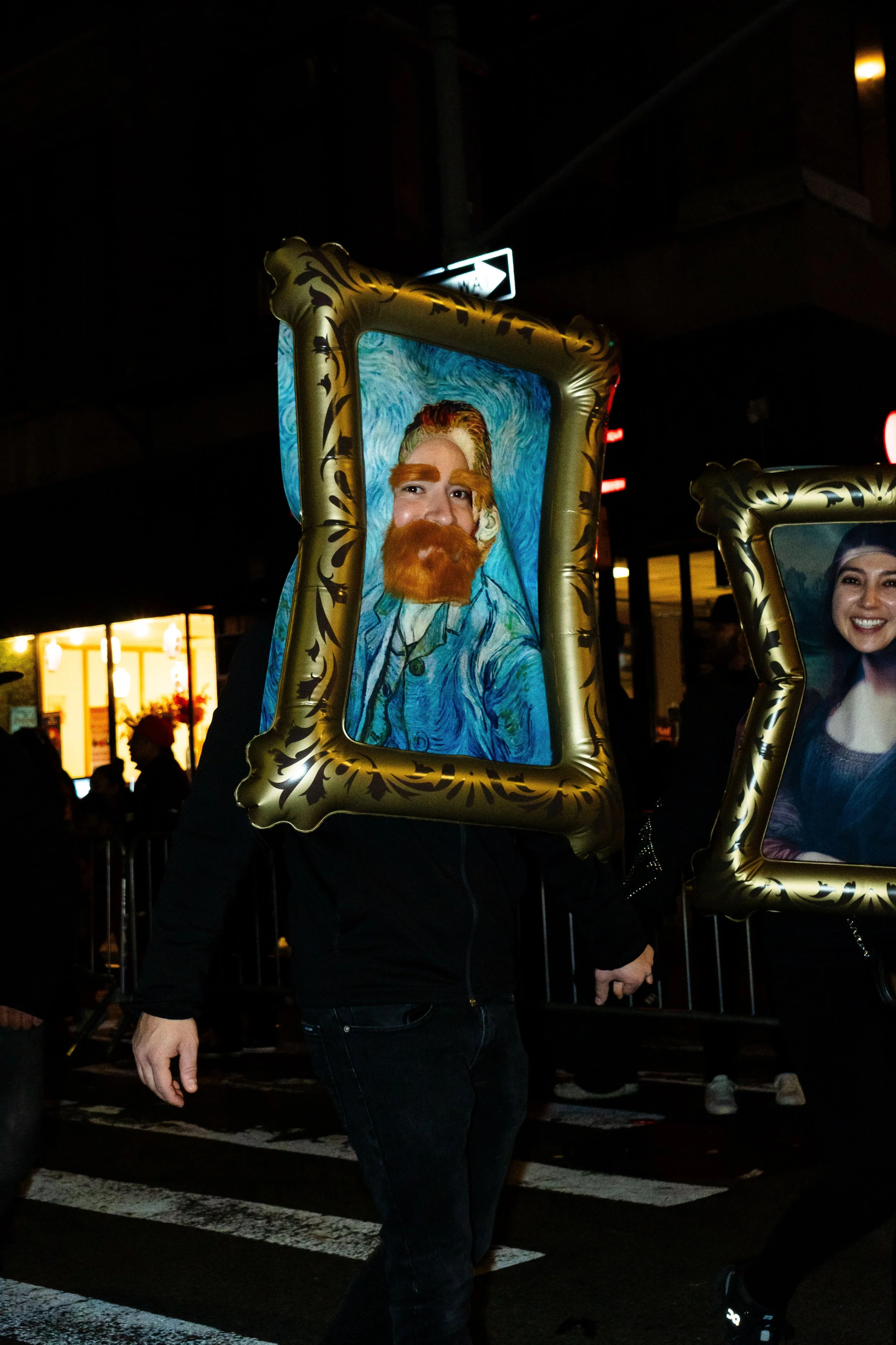 Person wearing a frame with a painted portrait of Vincent van Gogh's self-portrait at night.