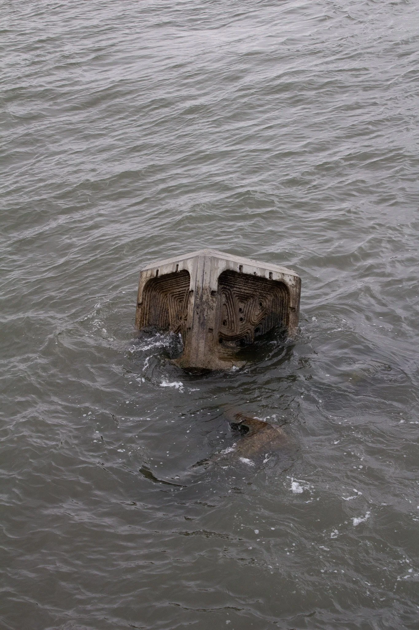 A sunken boat or platform partially submerged in water, with only the top visible.