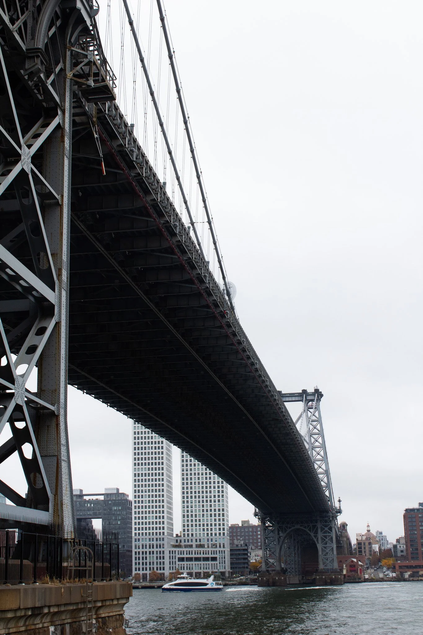 View of a large bridge over water in an urban area with skyscrapers and buildings in the background.