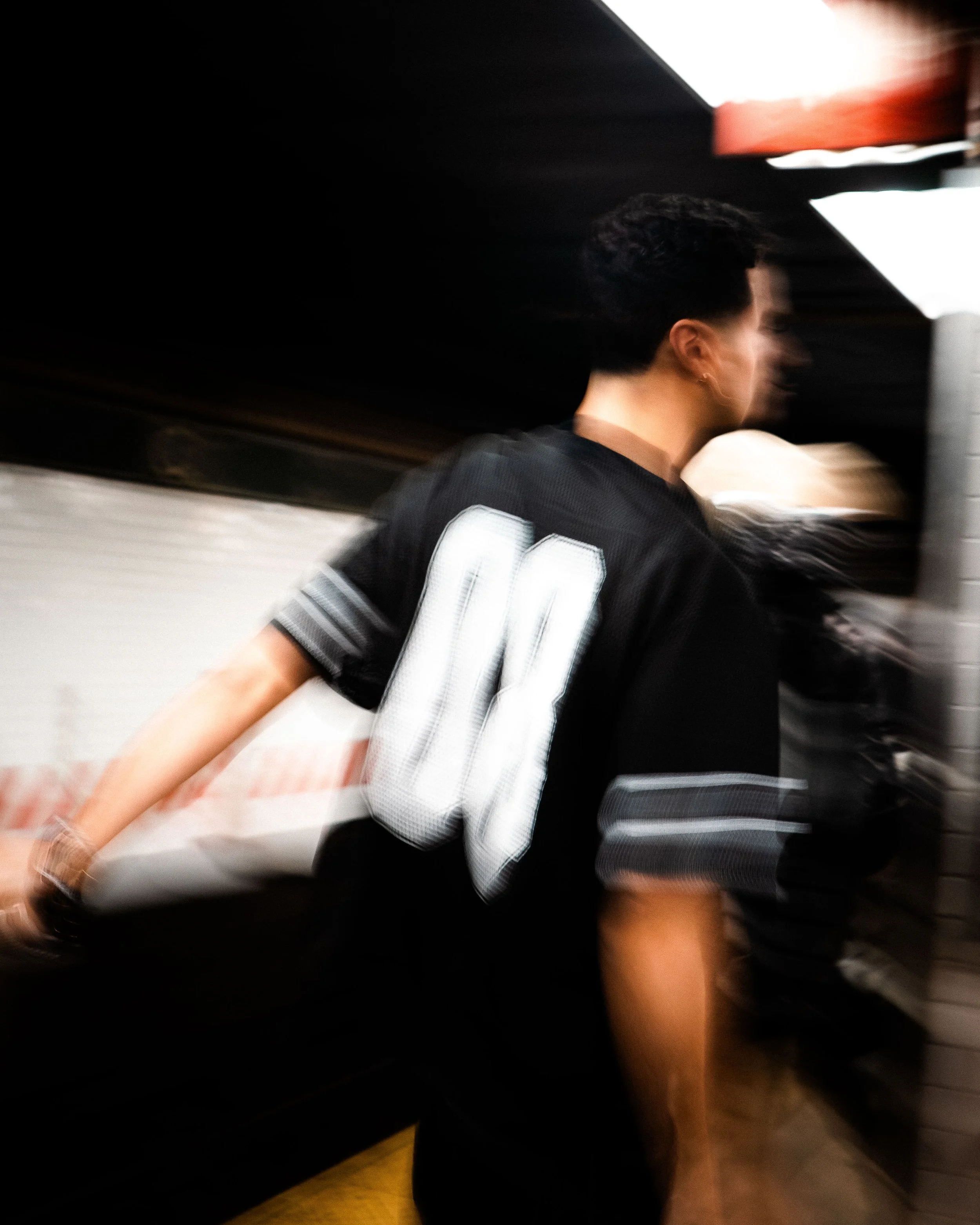 A person wearing a black sports jersey with the number 04, captured in motion, with a blurred background and motion effects.