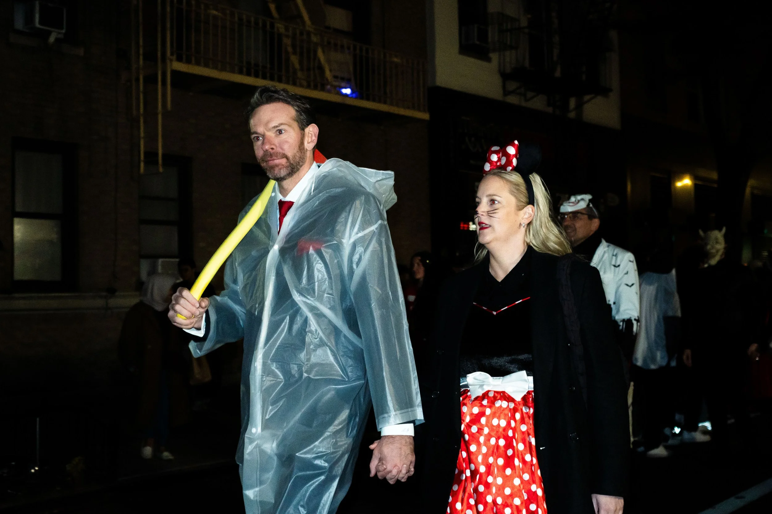 People in costumes walking in a parade at night.
