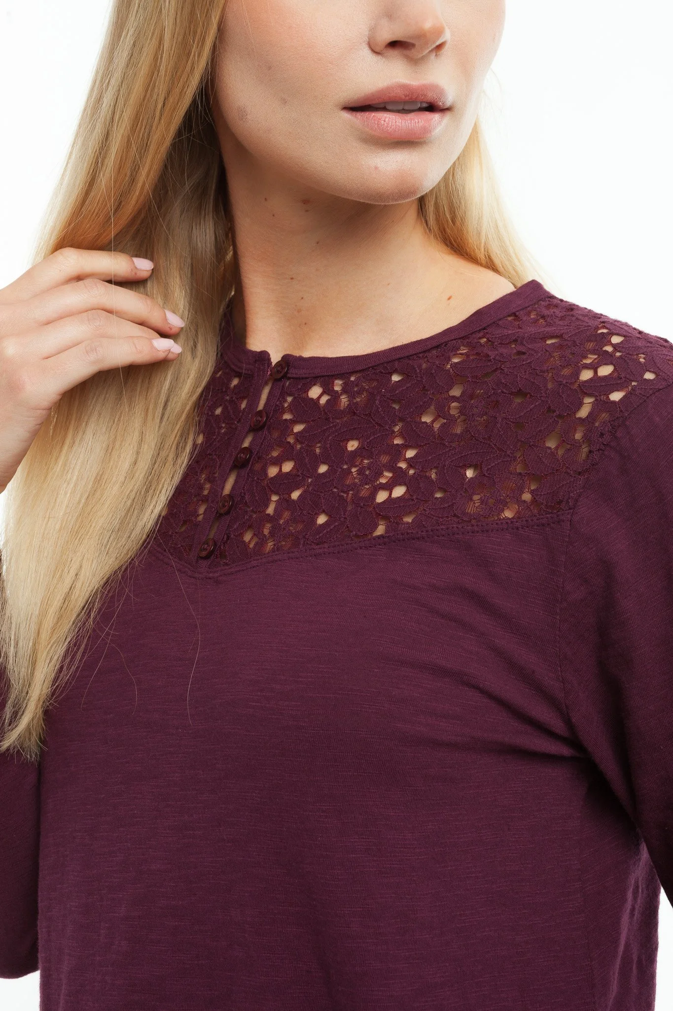 Close-up of a woman with blonde hair wearing a burgundy top with lace detailing near the collar.
