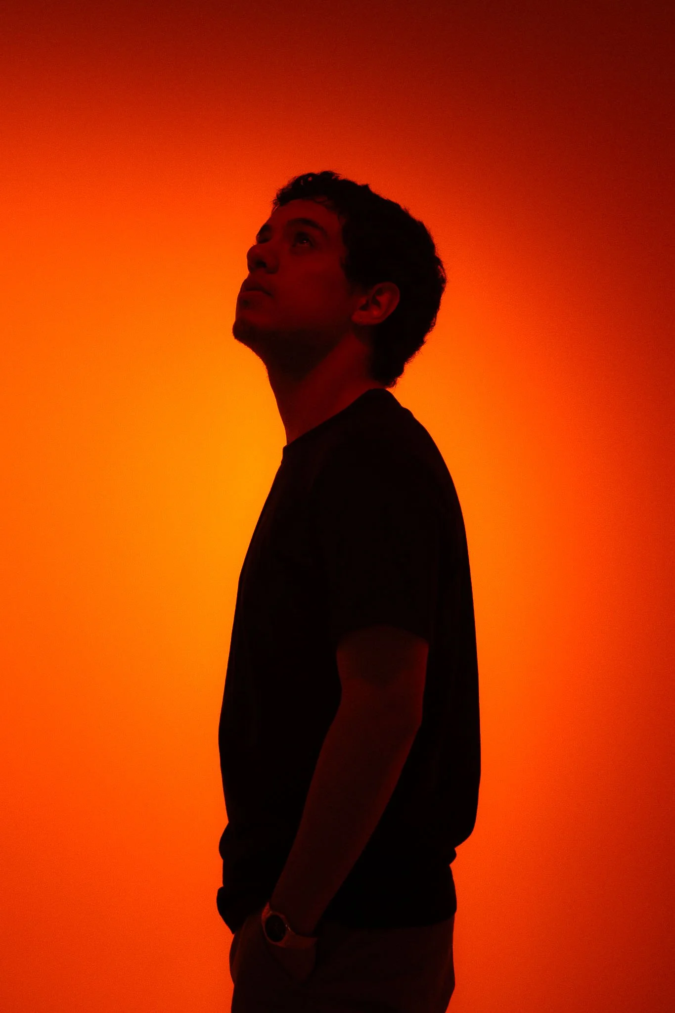 Silhouette of a man looking upwards against an orange and red gradient background.