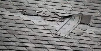 Broken roof shingles and a detached piece of roofing material.