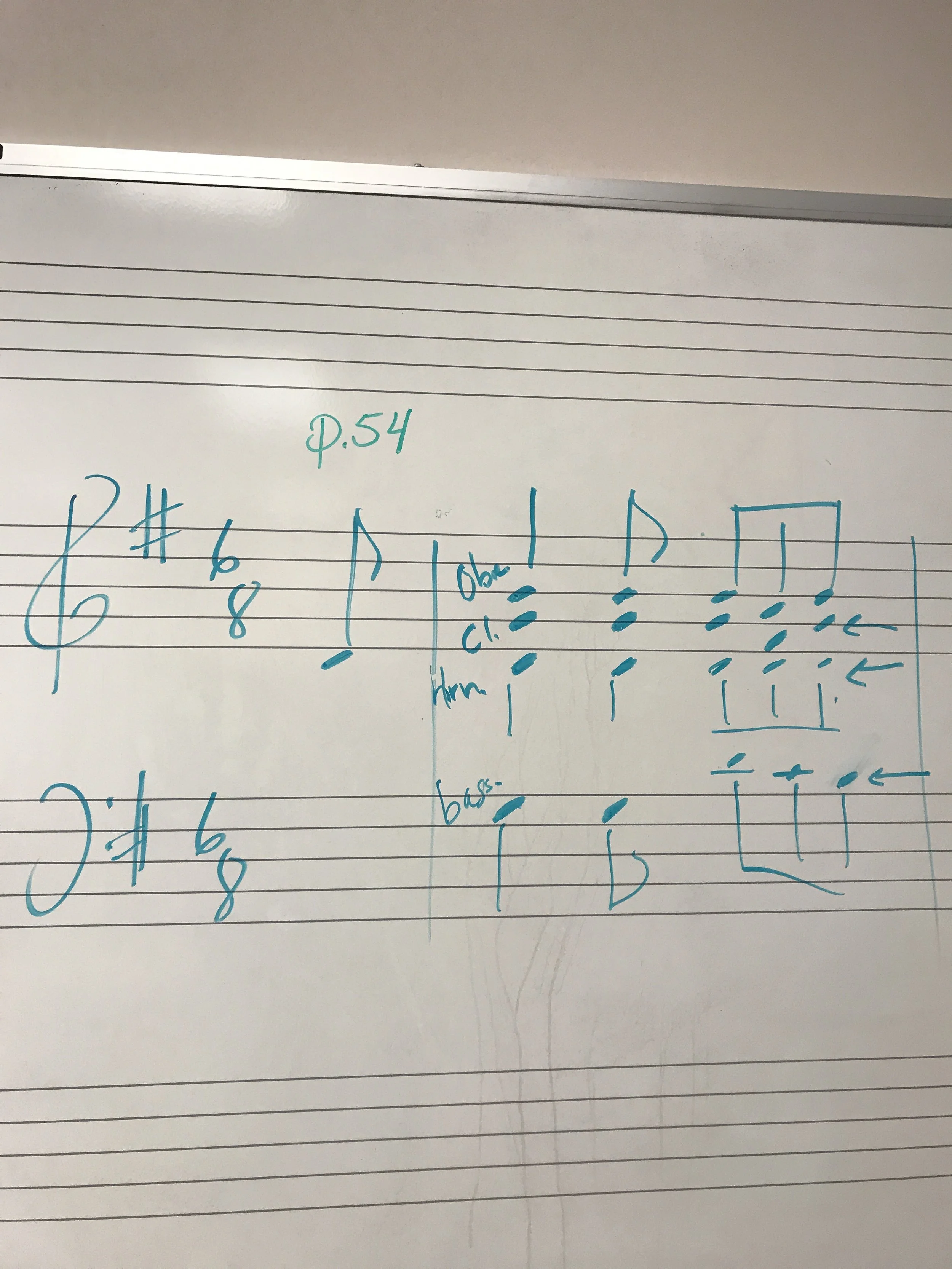 Whiteboard with musical notation, including chords, notes, and rhythm markings written in blue marker.