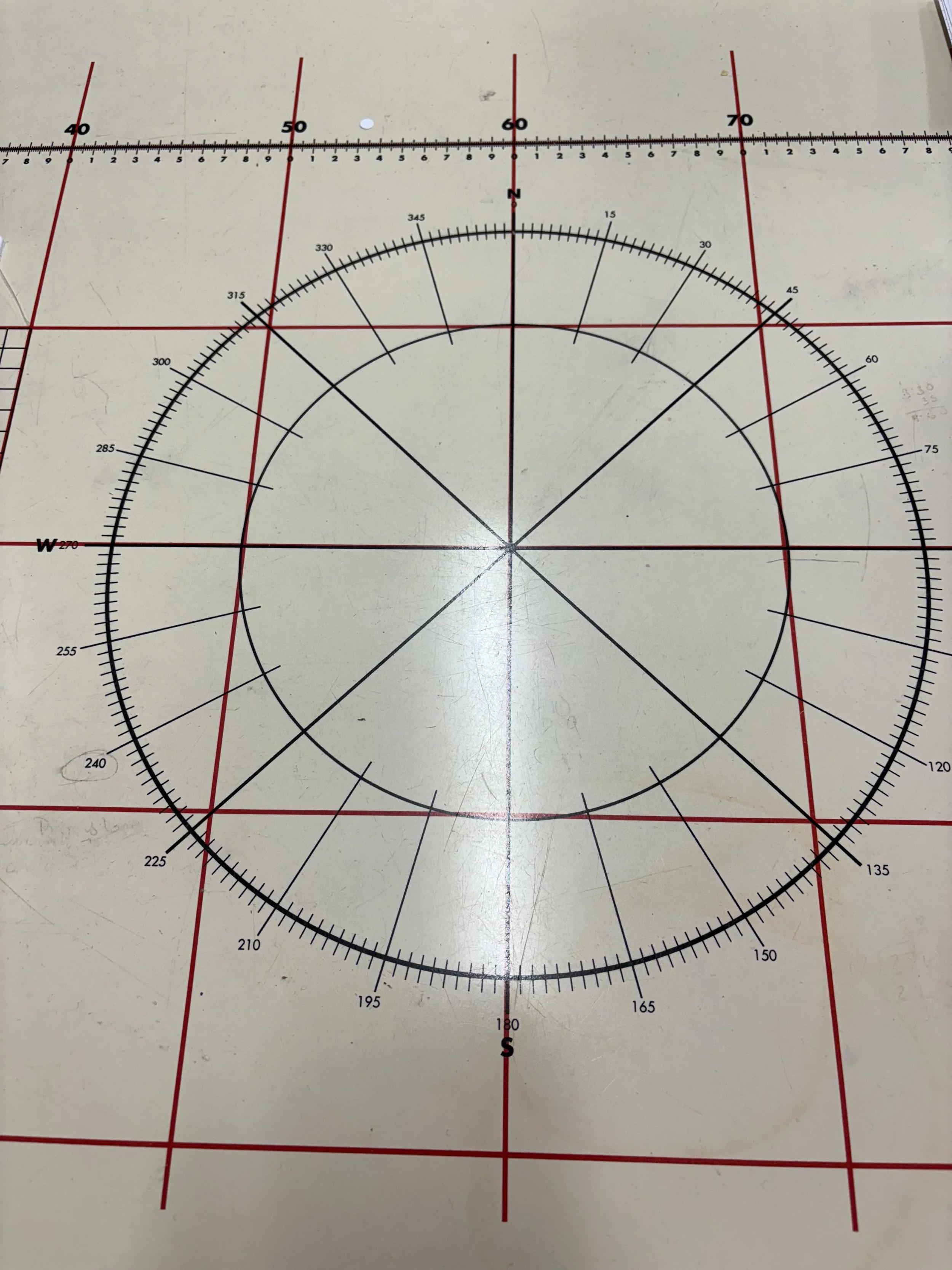 A white cutting mat with red grid lines and a black protractor circle with degree markings is shown in the image.