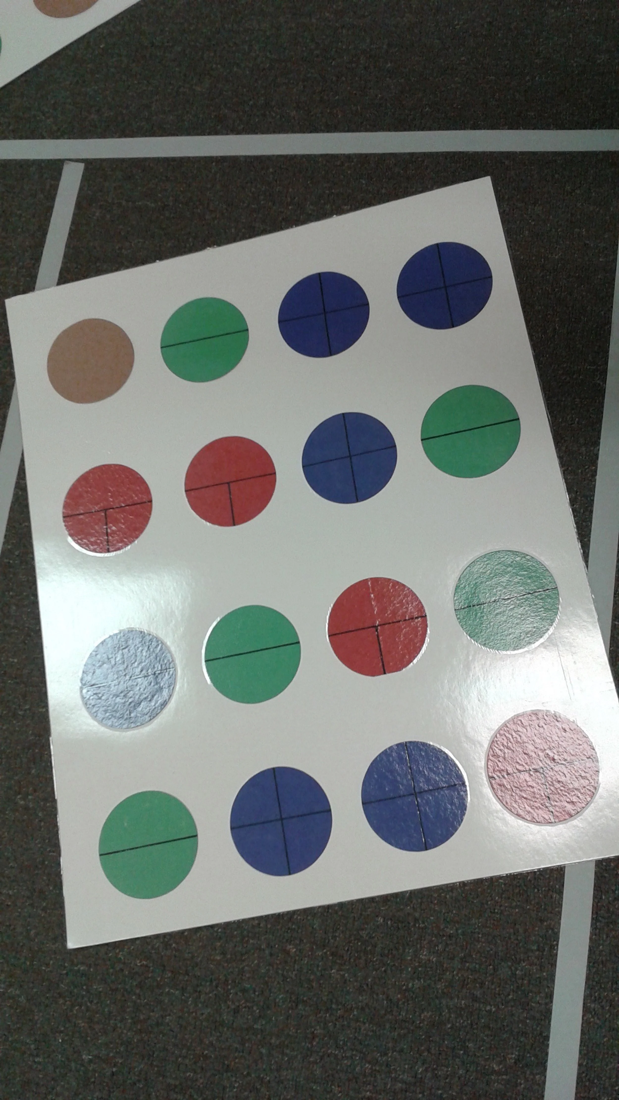 Sheet of circular stickers in various colors, including brown, green, blue, red, light blue, and pink, with black lines dividing each circle into four sections.