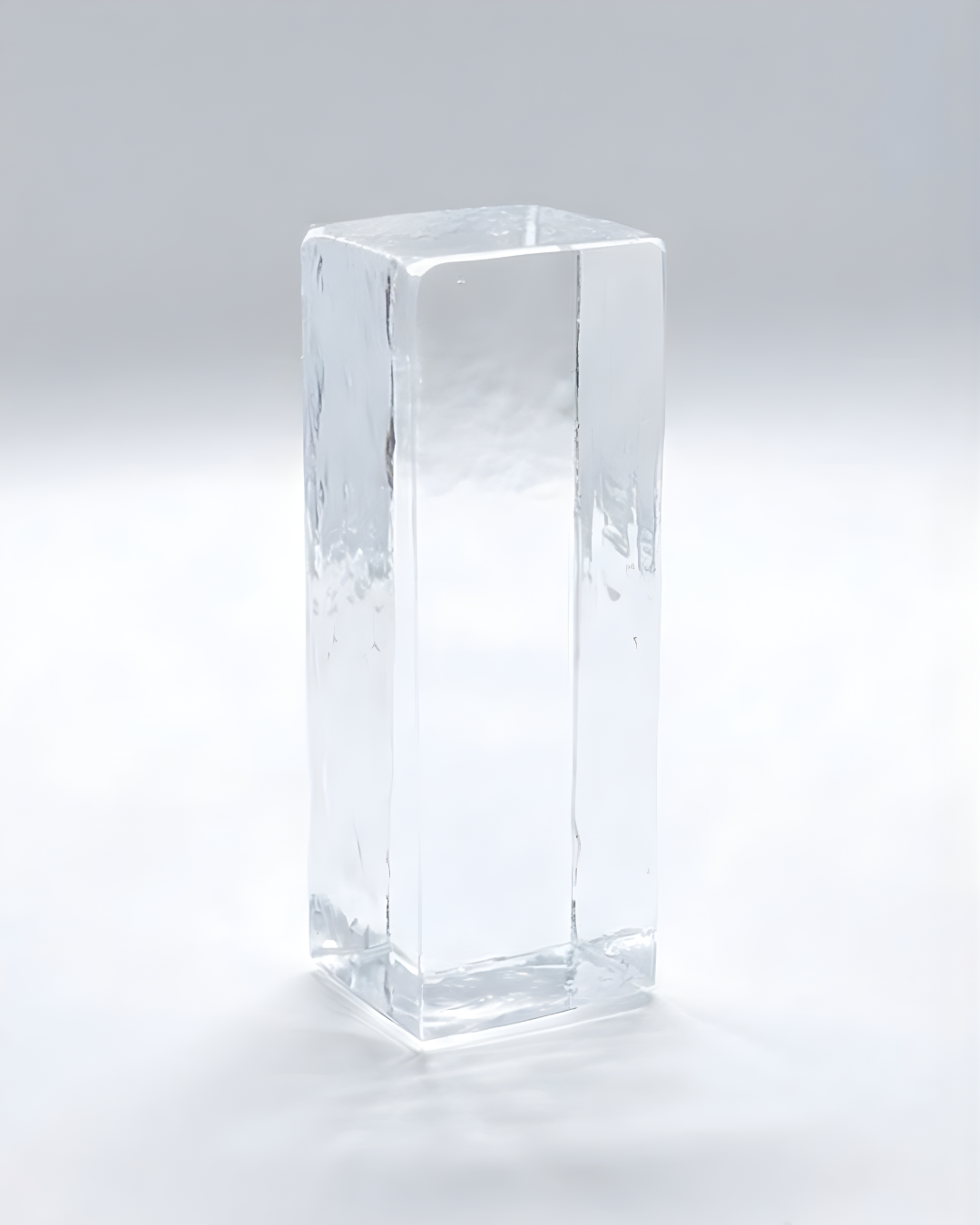 A clear ice cube with smooth edges and a rectangular shape, against a plain white background.