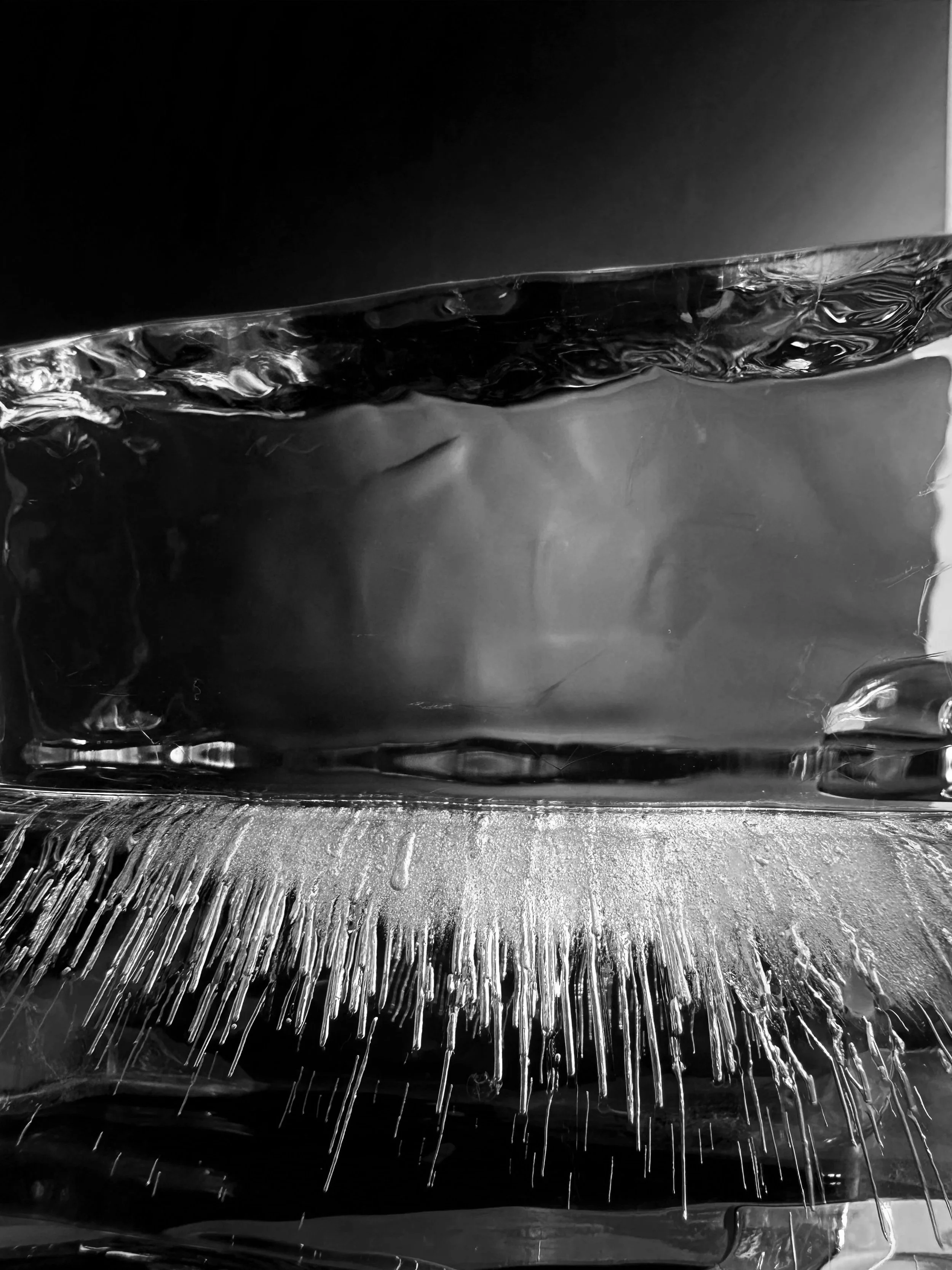 Close-up of a metallic object with water pouring over it and ice crystals forming on the surface