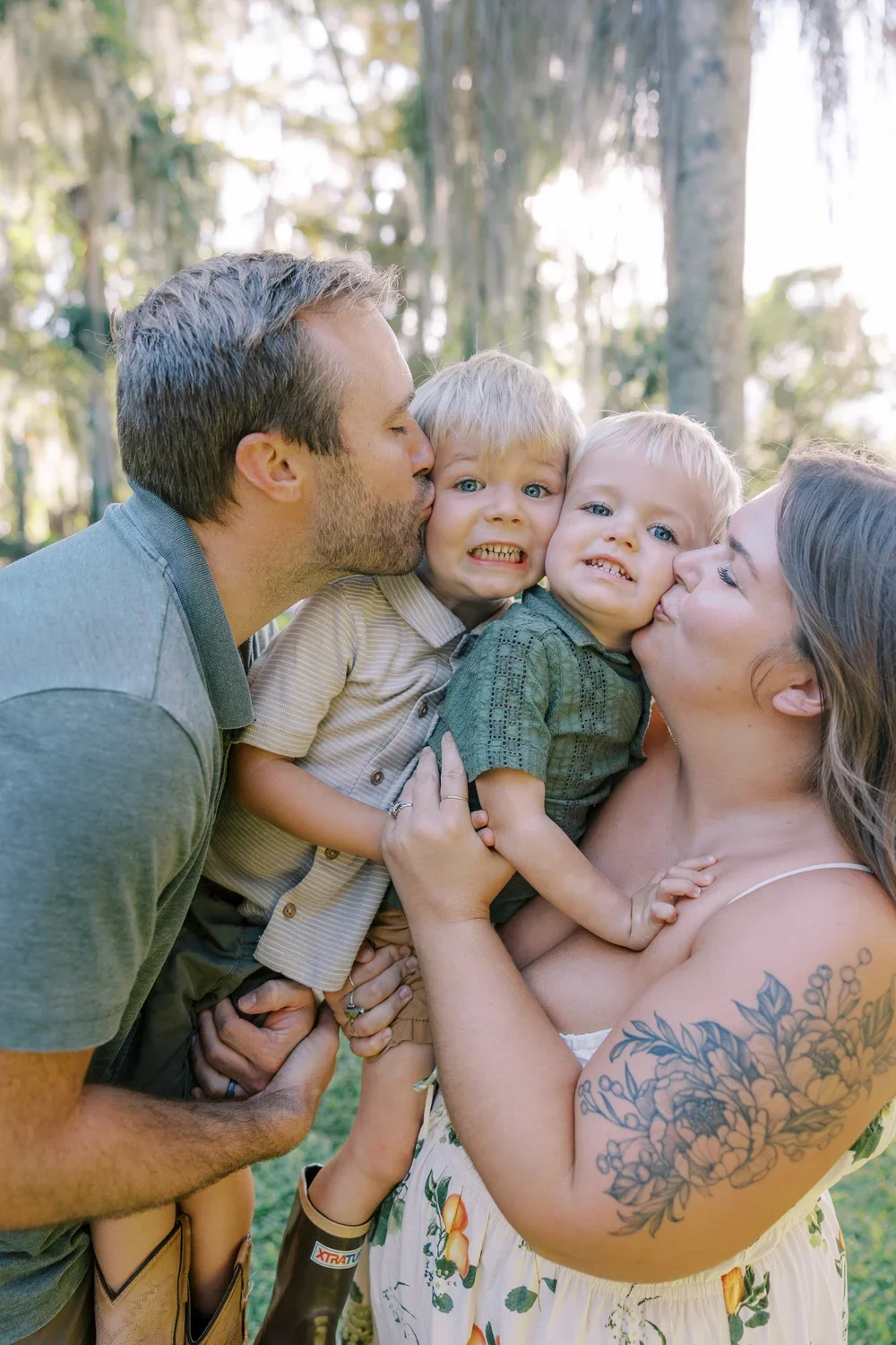 Parents give two young sons cheek kisses in their family portrait session in Orlando Florida