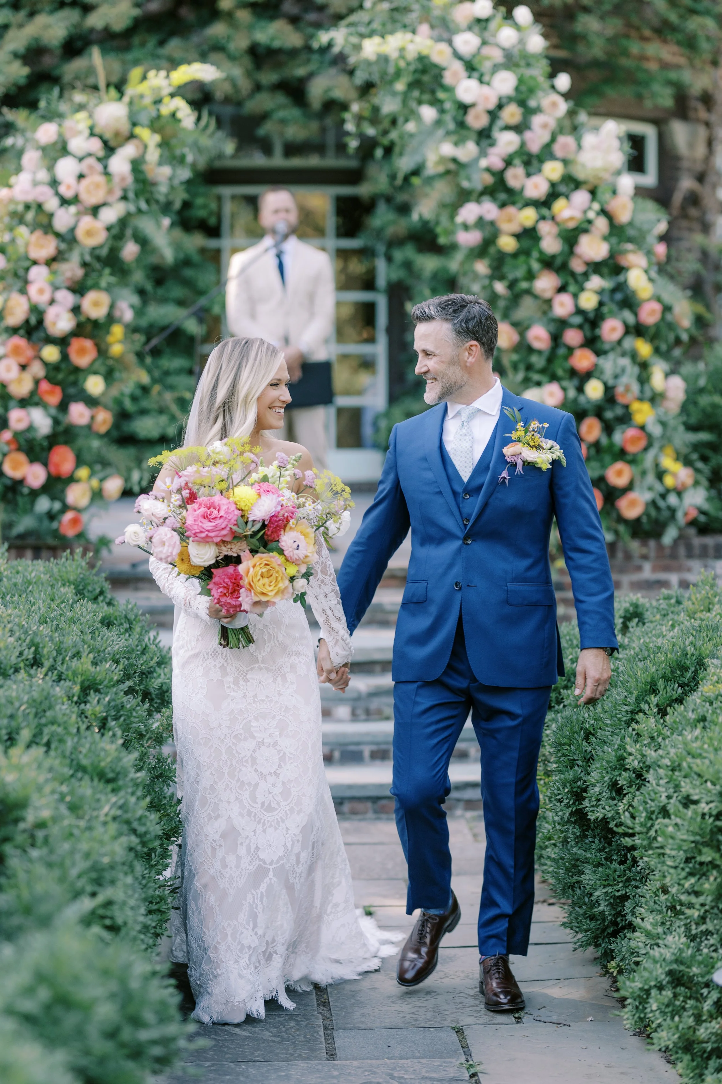 Bride and Groom smile and hold hands walking back up the aisle after their wedding ceremony photos by an Orlando Florida wedding photographer