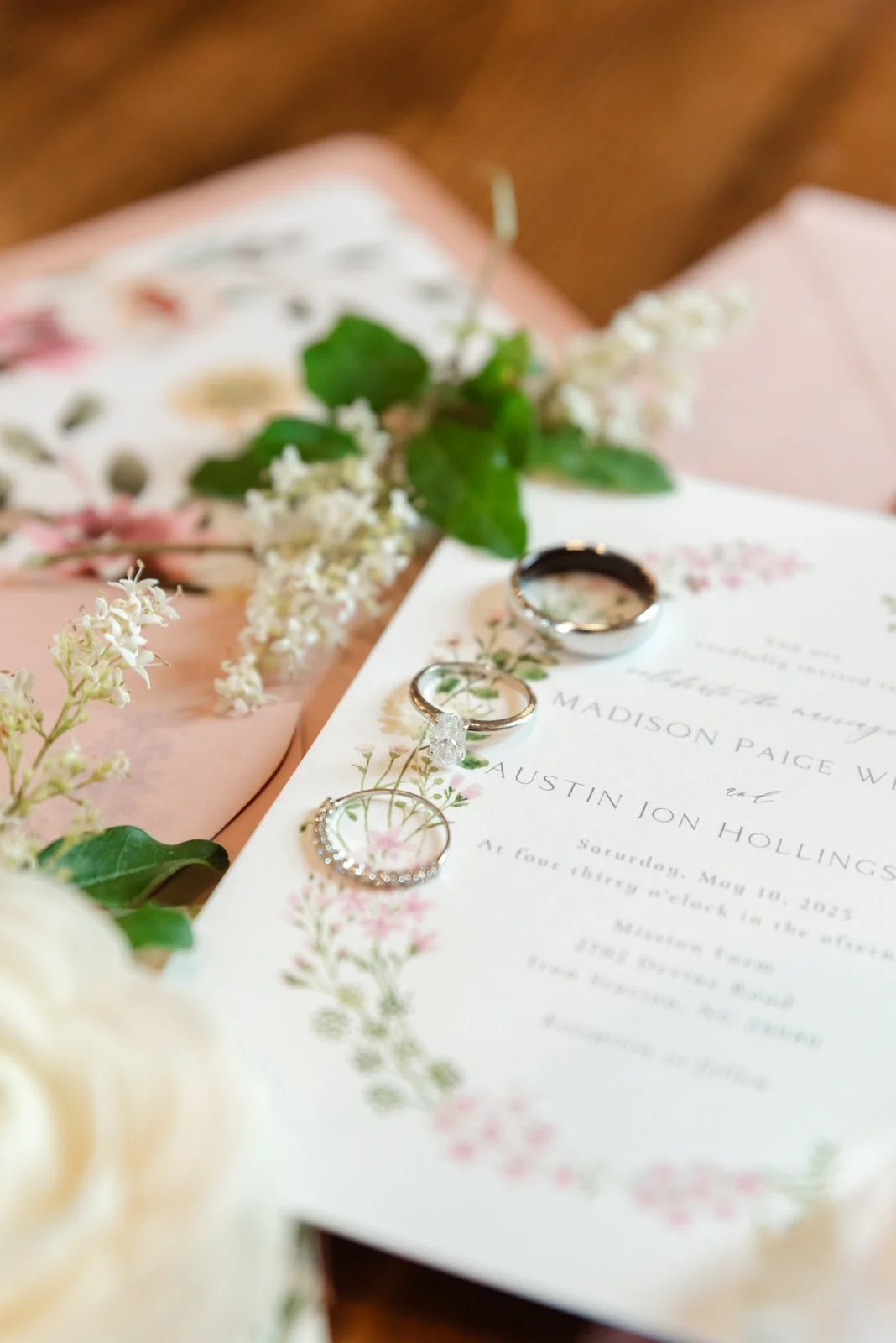 Wedding invitation with wedding rings and wedding dress fabric in the background.