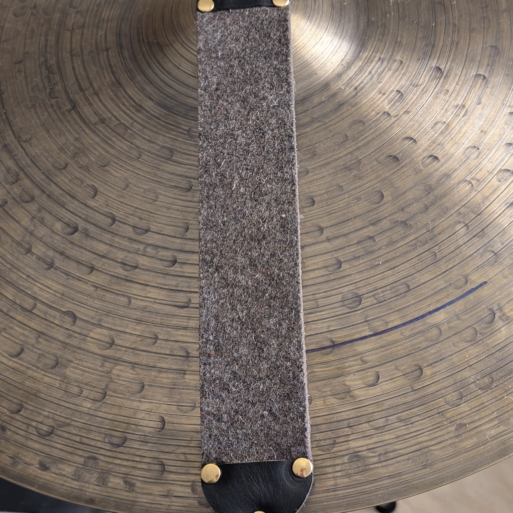 Close-up of a cymbal with a felt strip with leather caps and rivets
