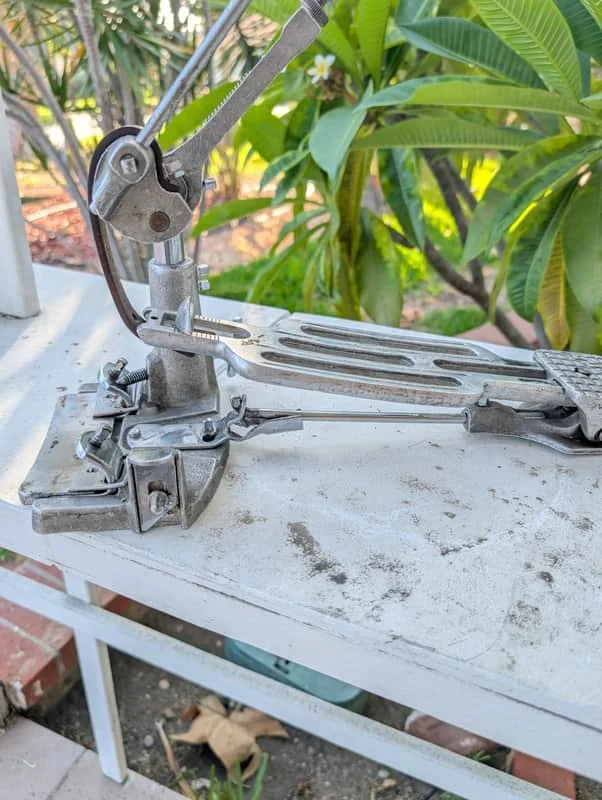 vintage drum pedal on white shelf
