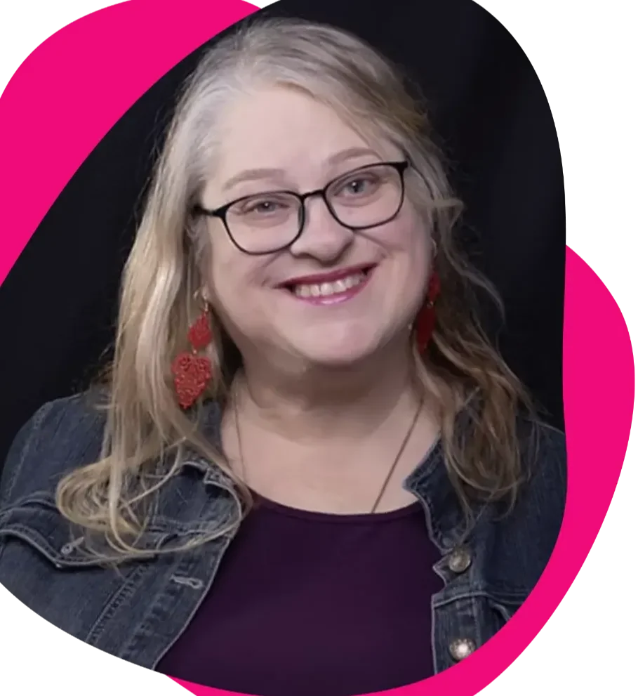 A woman with blonde hair, glasses, and red earrings smiling at the camera, wearing a denim jacket over a dark top, with a dark background and a pink curved design.