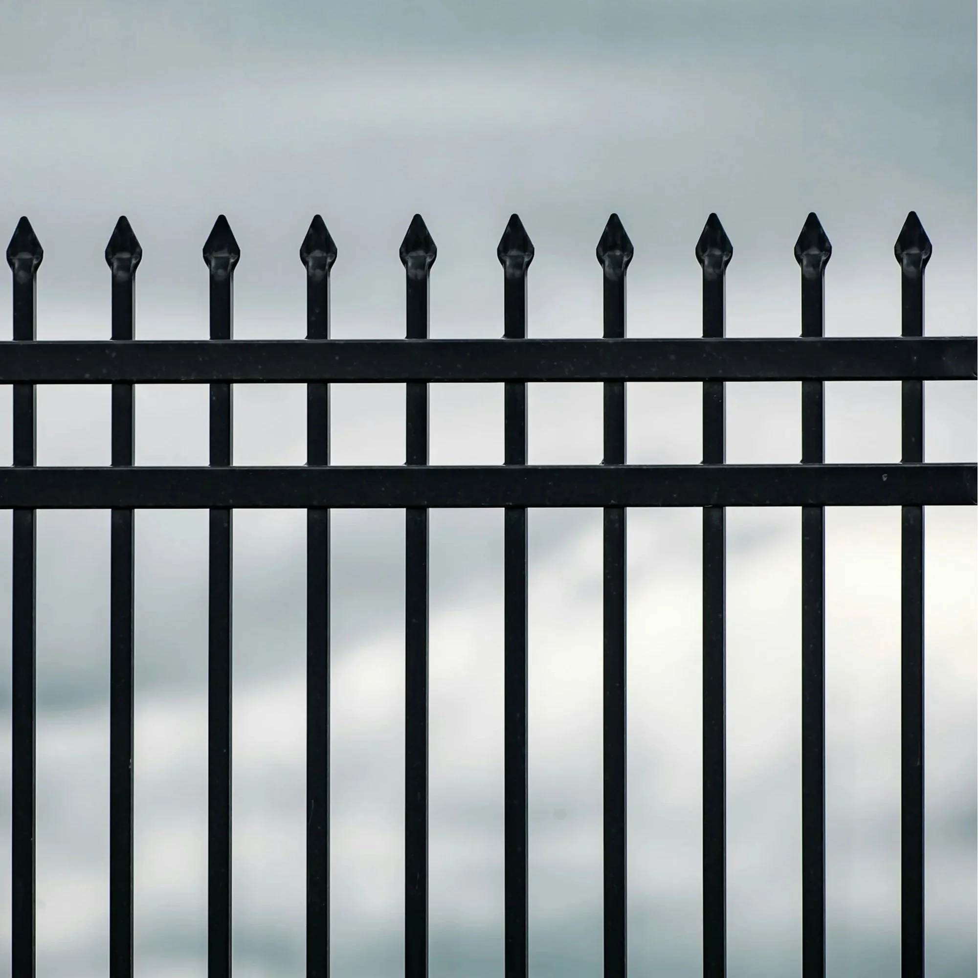 Close view of black metal fence with pointed tops, representing durable perimeter security and professional installation for residential community boundaries.