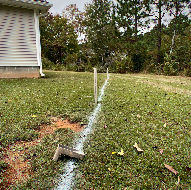 measuring tape marking fence posts on grass yard