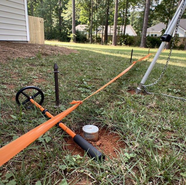 surveyor marking property line with wooden stakes in backyard