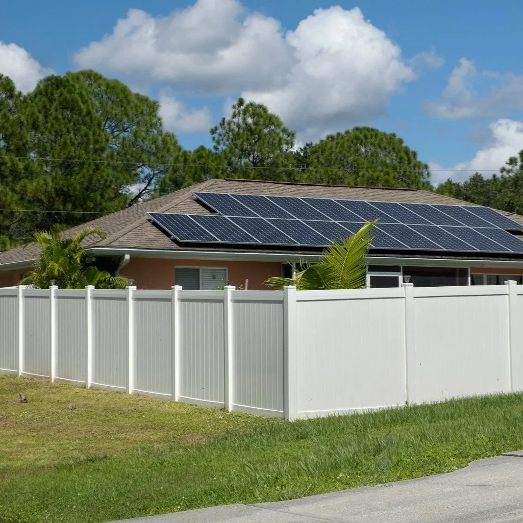 Modern house with rooftop solar panels behind tall white vinyl privacy fence, illustrating secure, weather-resistant fencing ideal for stylish residential properties