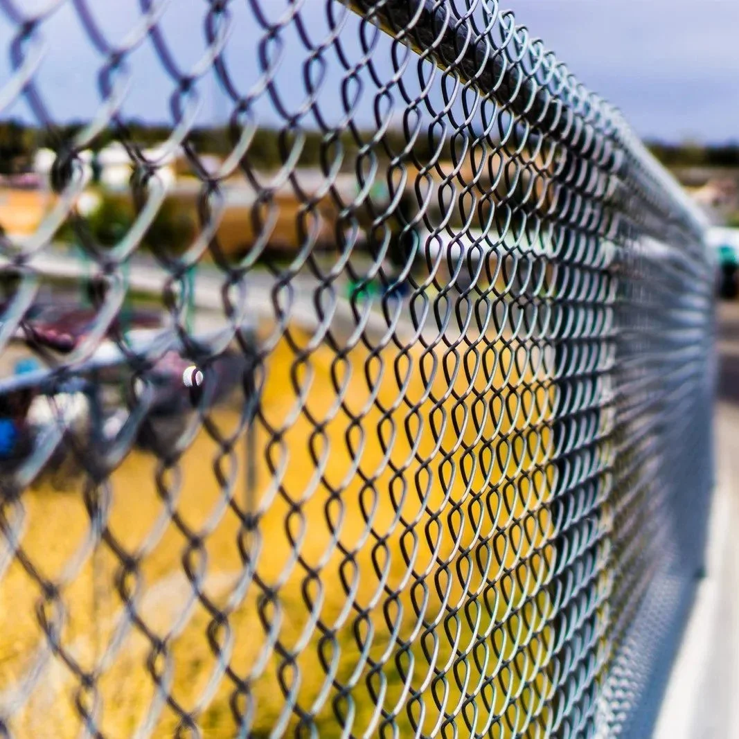 Detailed view of chain link fencing showing interwoven steel pattern, representing durable, transparent, and cost-effective solution for commercial perimeter security systems.