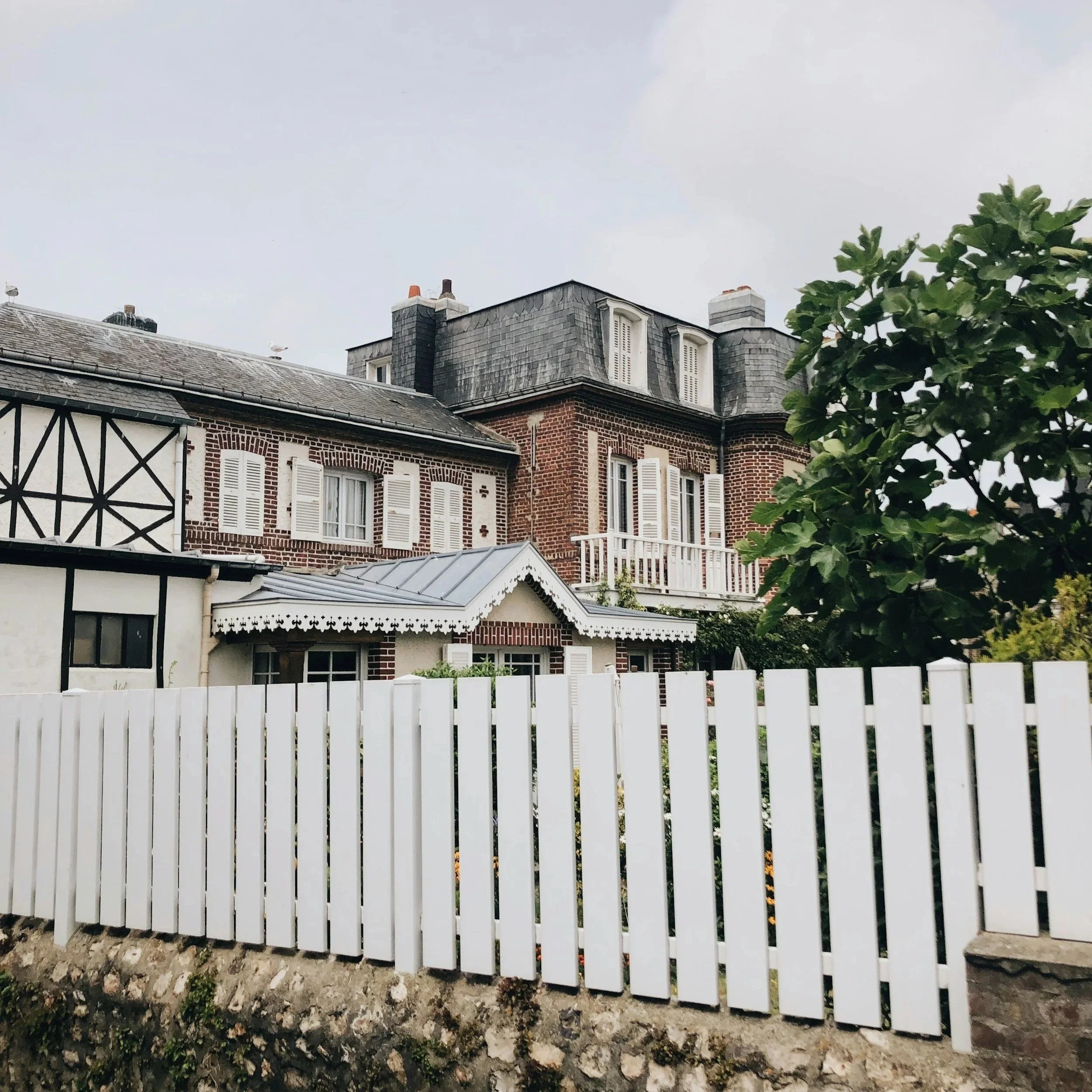 Tall white wooden fence in front of home, representing cedar fencing benefits including privacy, weather resistance, and long-lasting professional installation quality.