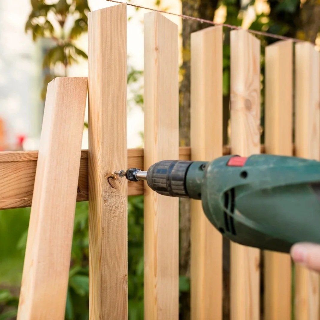 Close-up of drill fastening screw into wooden fence slat, illustrating professional fence installation process ensuring stability, alignment, and long-term structural strength.
