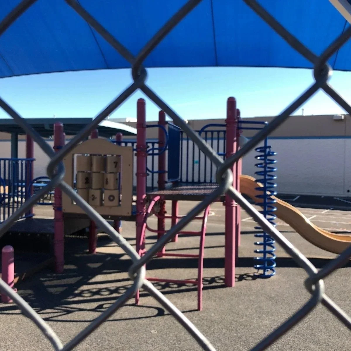Playground equipment behind chain link fence, illustrating secure boundary design, child safety, and durable installation used in professional playground fencing systems.