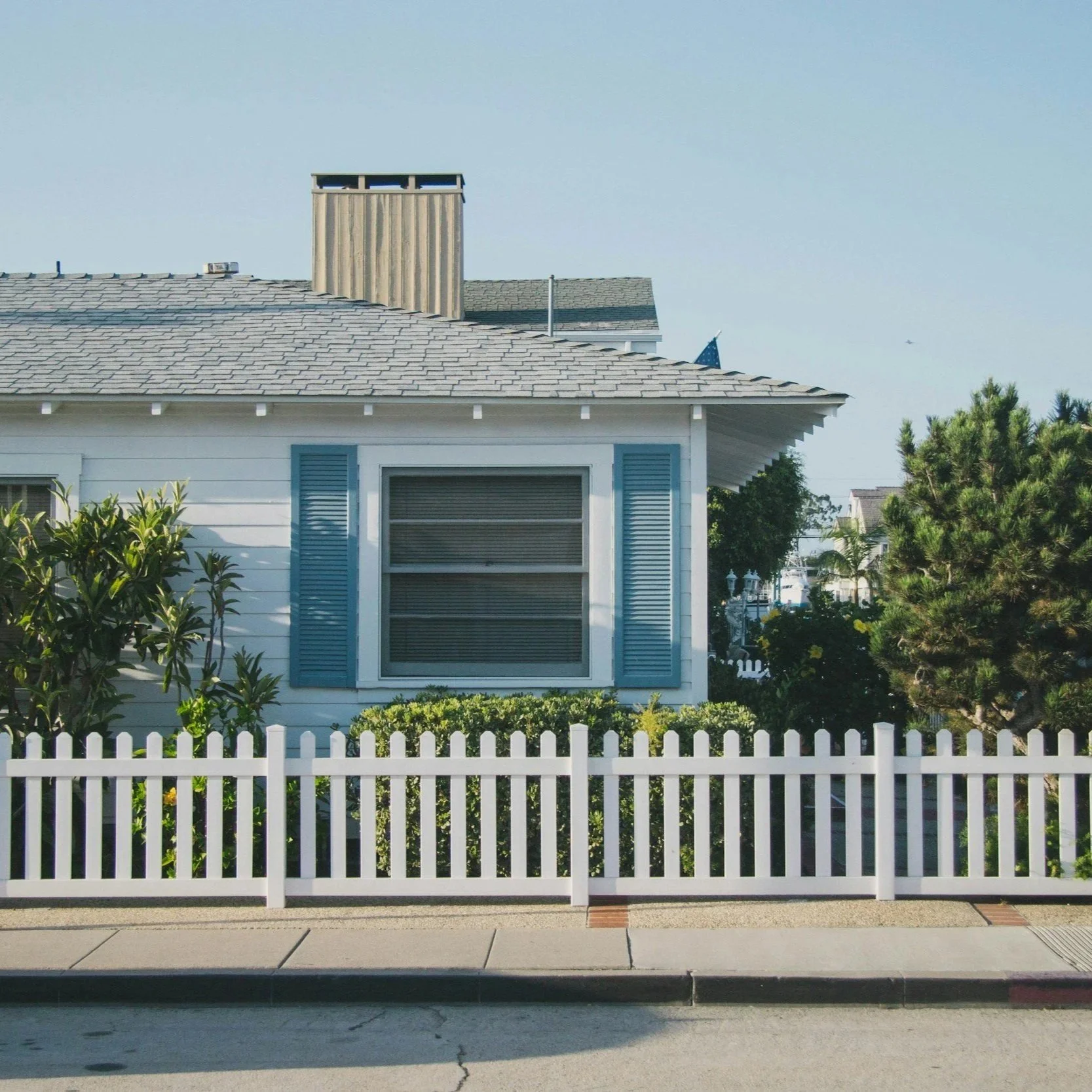 White picket fence in front of home, illustrating precision installation, structural strength, and visual appeal aligned with commercial fencing quality standards.