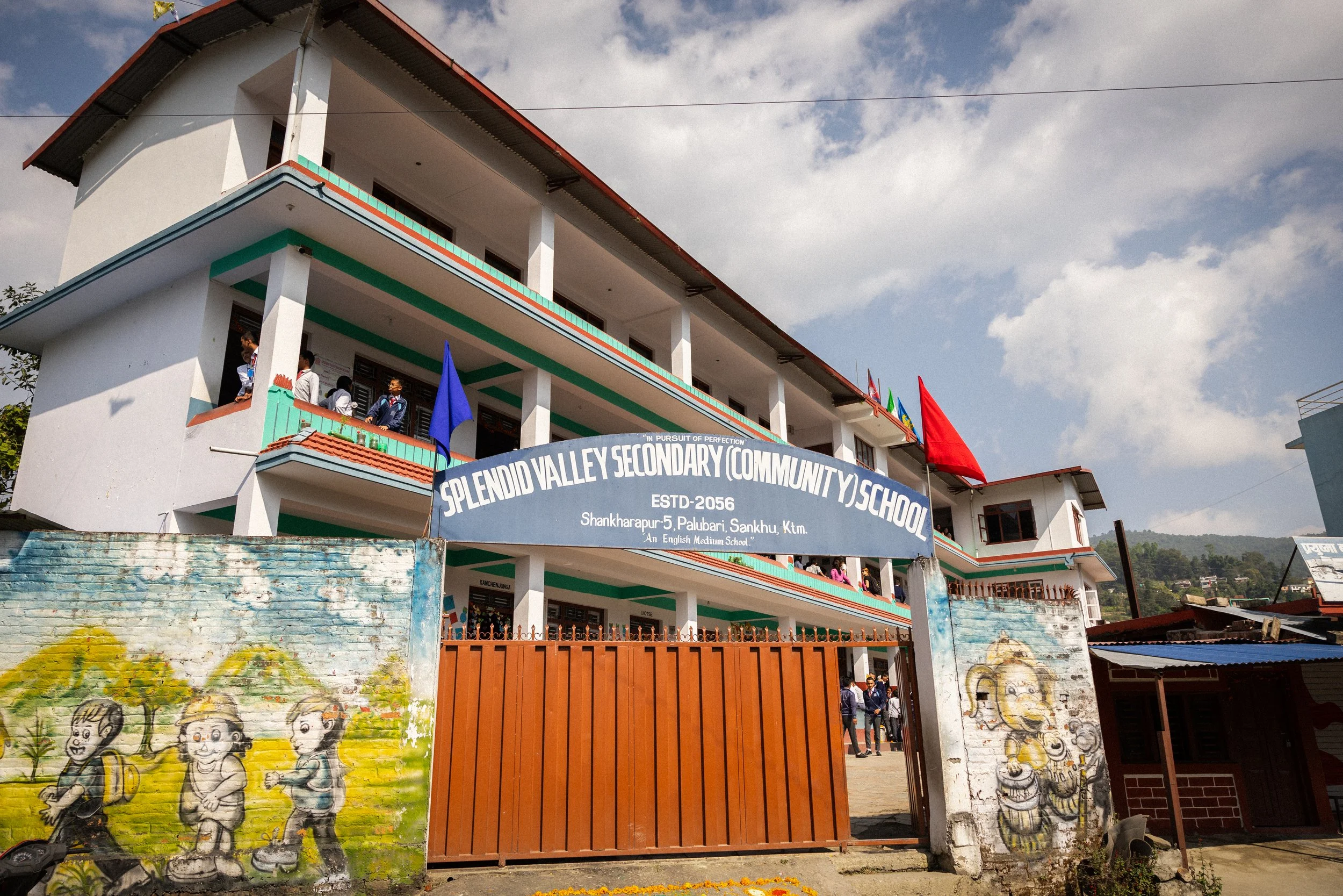 Scuola secondaria chiamata Splendid Valley Community School con studenti all'interno e graffiti su i muri esterni.