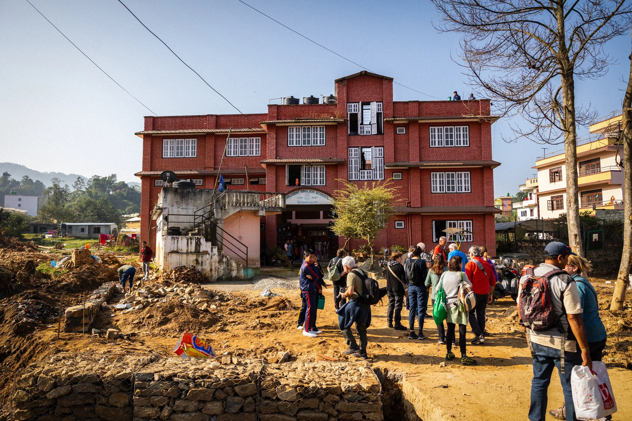 Gruppo di persone davanti a un edificio rosso in una zona in costruzione o in rinnovamento.