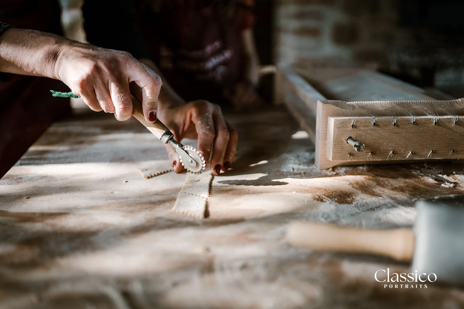 Close-up of a person using a small hand tool to cut fabric on a workbench in a workshop. The scene includes a wooden frame, fabric pieces, and dust on the surface.