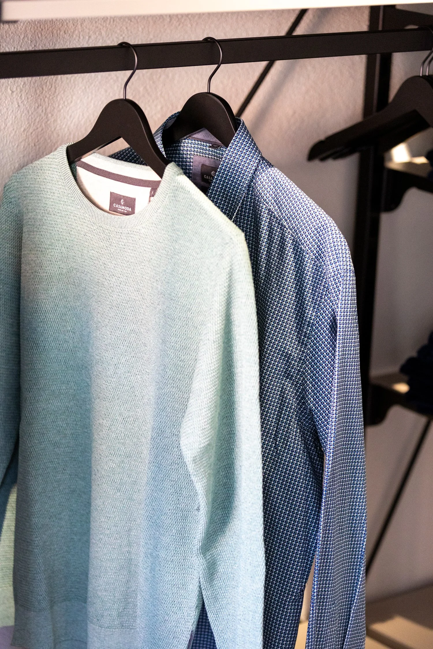 Herren-Hemd und Pullover auf Kleiderbügel in einem Geschäft