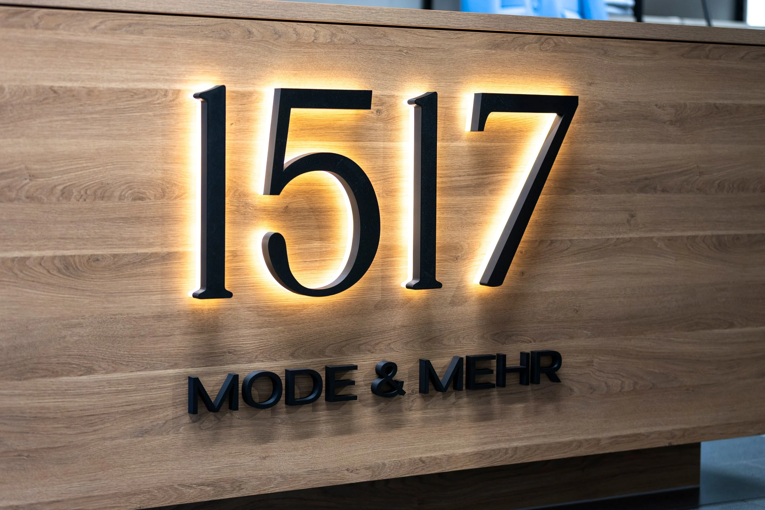 Schriftzug mit der Nummer 1617 und der Bezeichnung MODERN & MÖBEL an einer Holzwand.