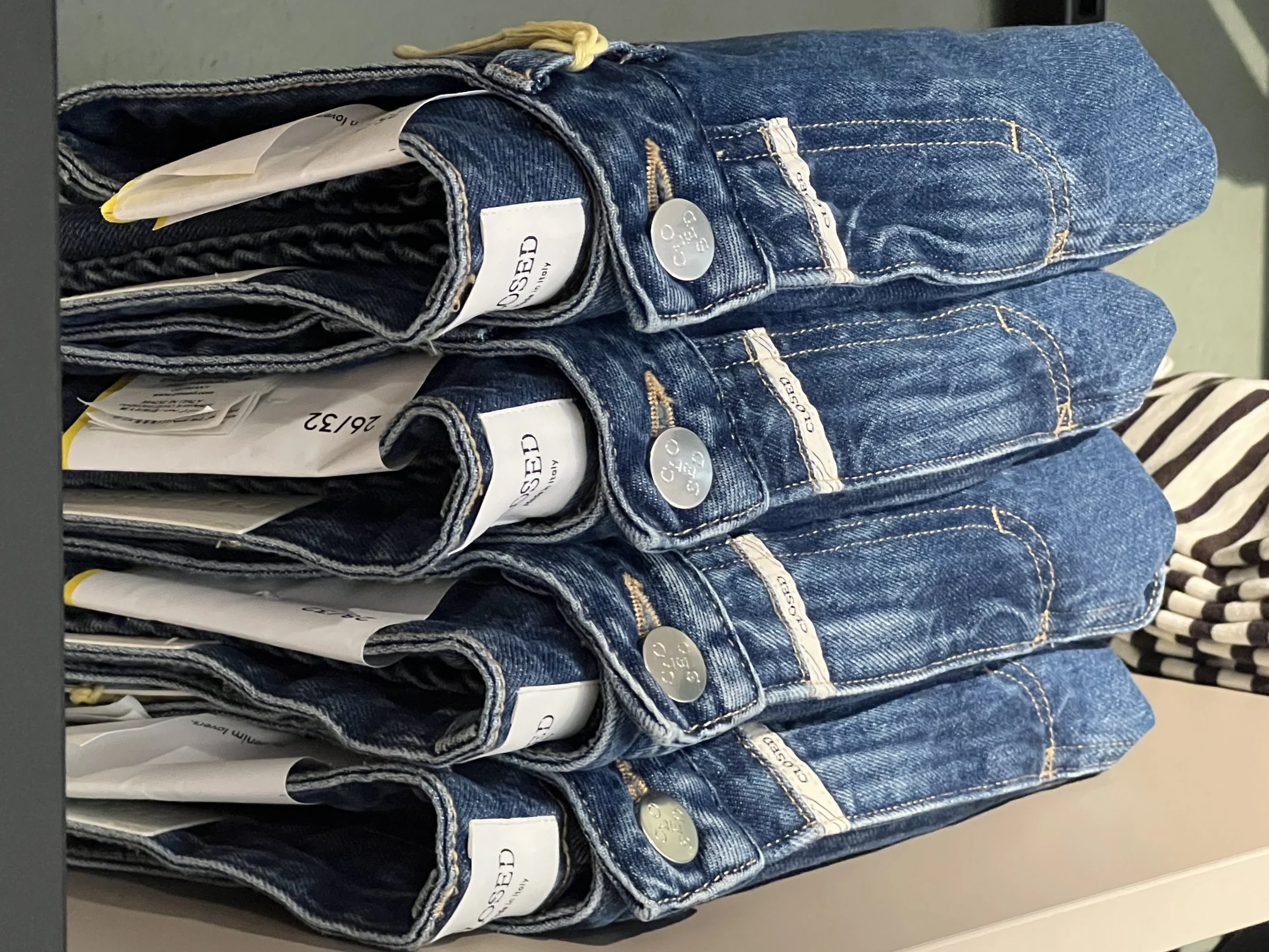 Mehrere Jeanshosen, gefaltet und in einer Verkaufshalle gestapelt.