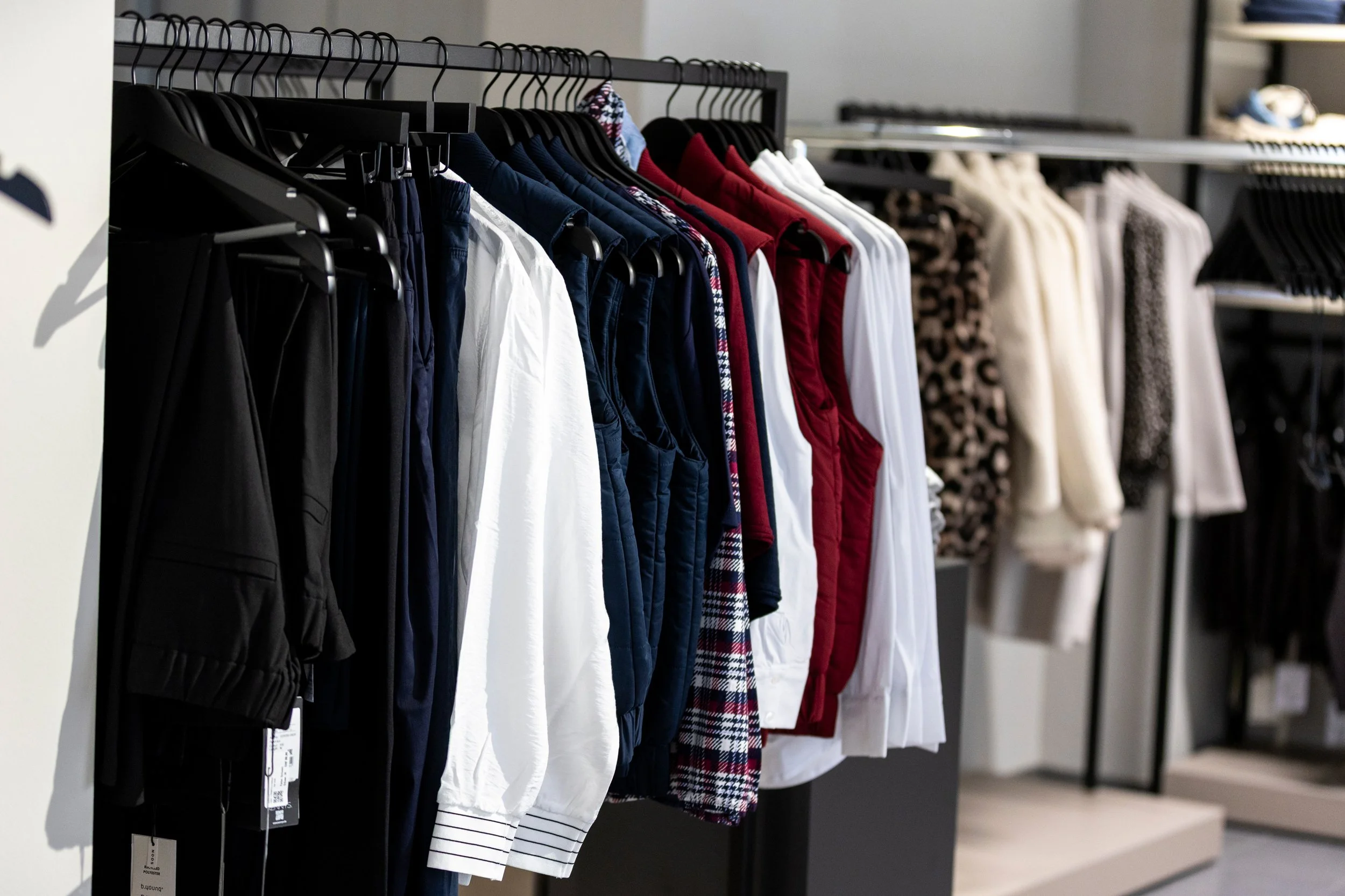 Kleiderstange mit Kinderbekleidung in verschiedenen Farben und Mustern in einem Kleiderschrank
