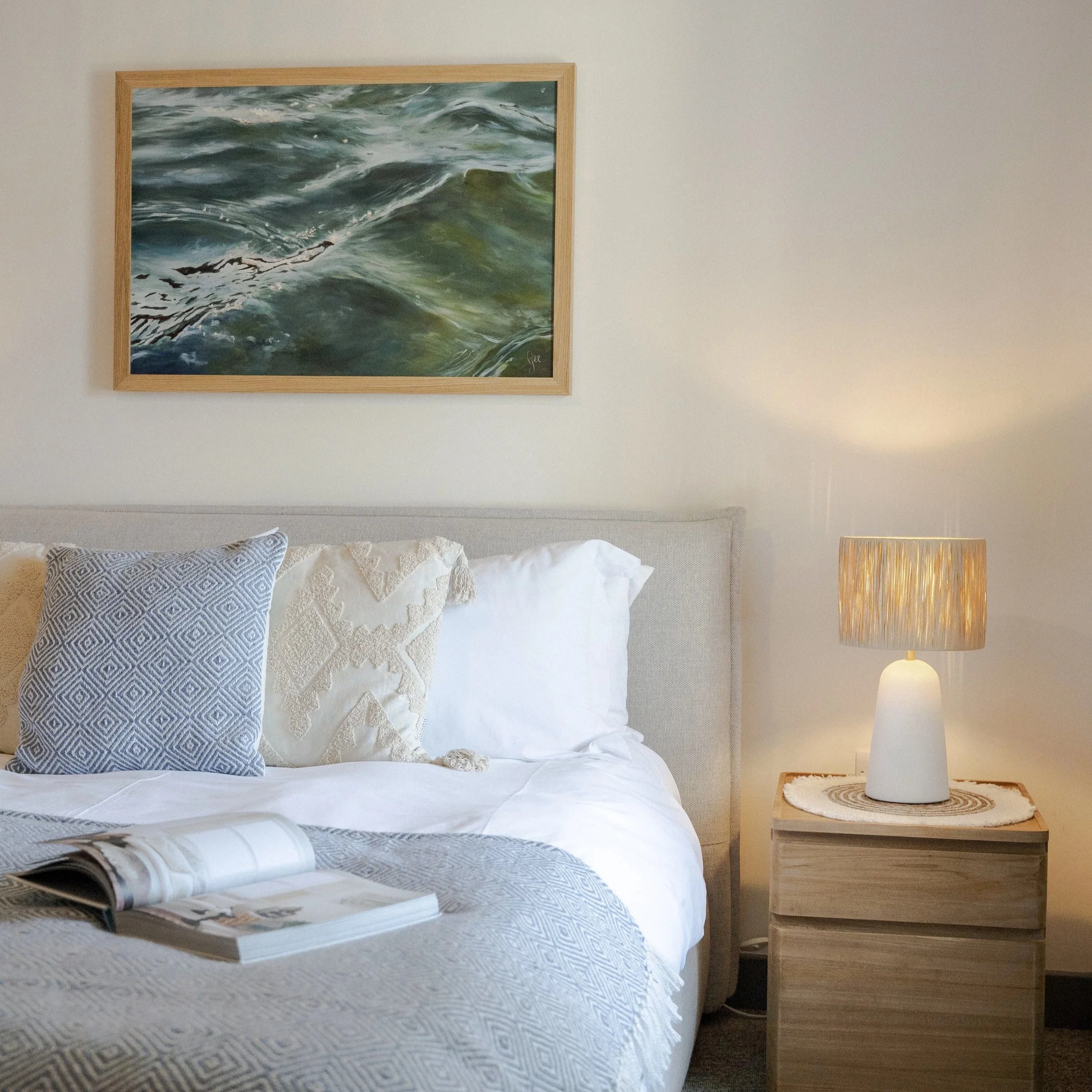 Bedroom at Stargazey with soft white bedding and coastal wall art.