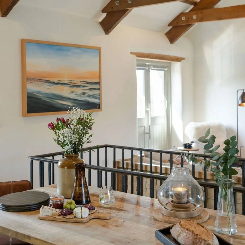 Dining space at Stargazey with wooden table and beams, filled with natural light.