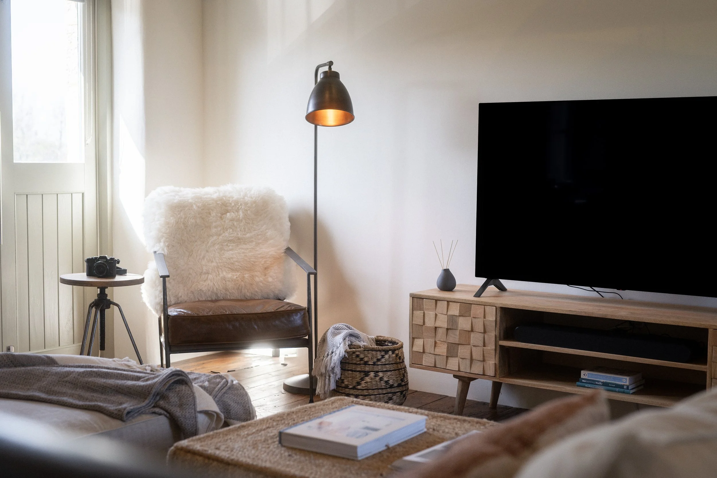 Sitting room at Stargazey barn — armchair, floor lamp and natural light through double doors