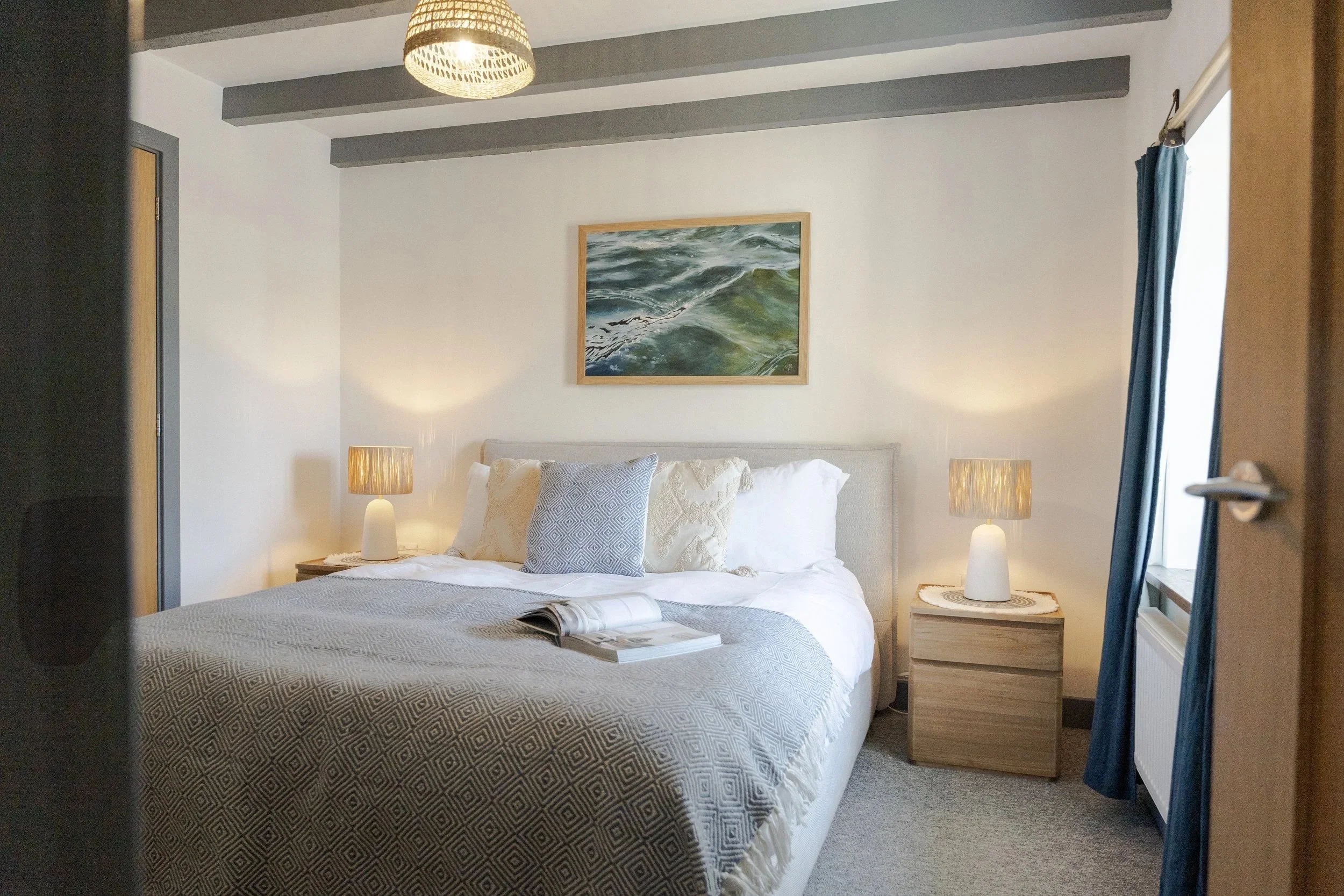 Bedroom at Stargazey with warm textures and coastal artwork, designed for slower living.