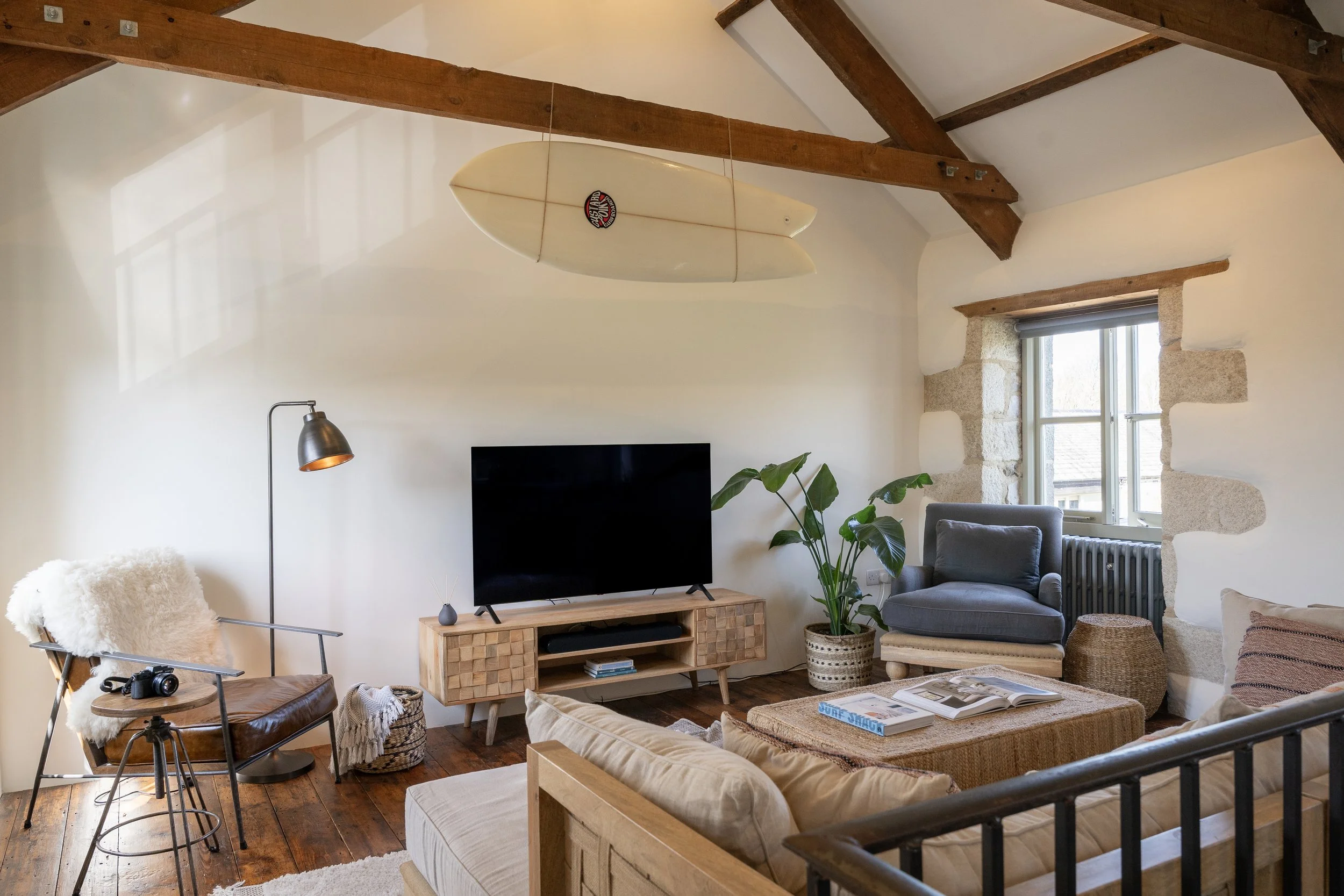Vaulted living room at Stargazey barn, Mawgan Porth — oak beams, suspended surfboard and warm natural textures